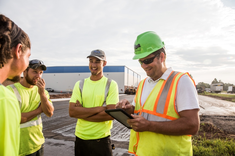 Construction crew holding a safety meeting on-site, discussing TRIR (Total Recordable Incident Rate) and workplace safety performance.